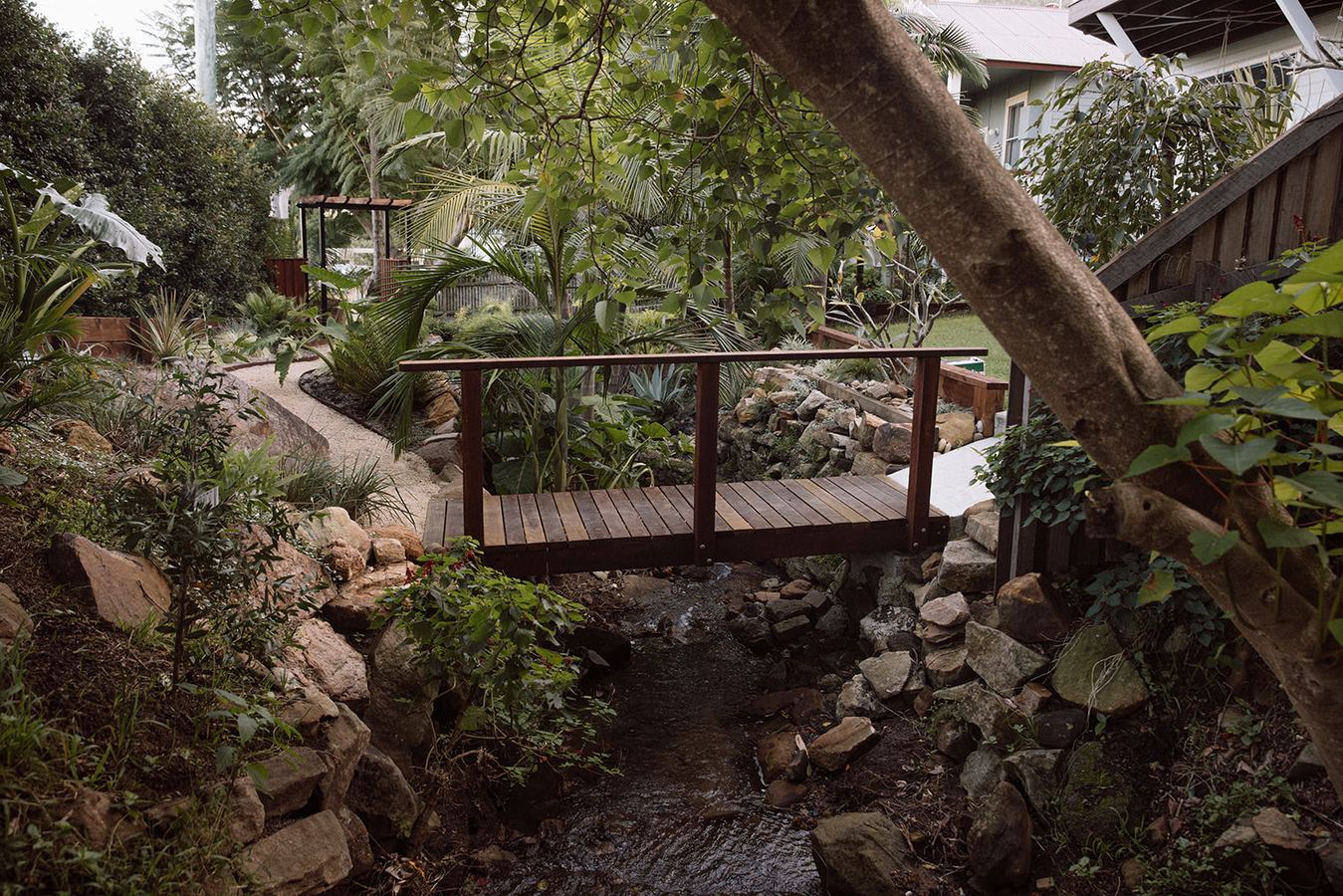 Timber footbridge crossing a small garden stream — waterway and bridge upkeep NSW